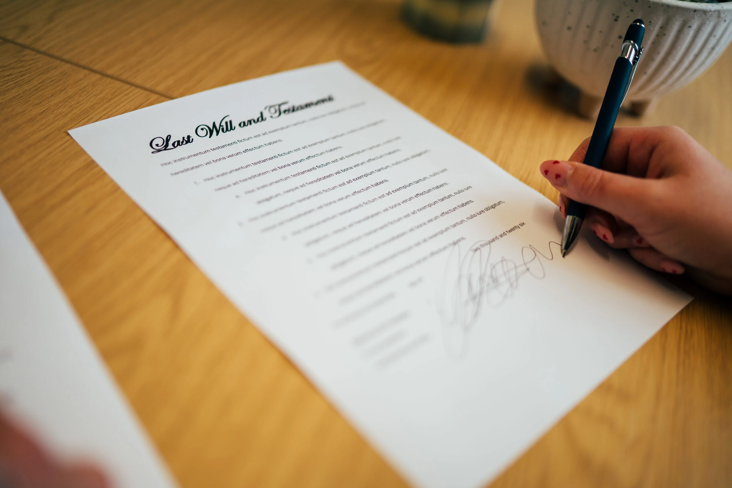 Hands signing a will document with a pen